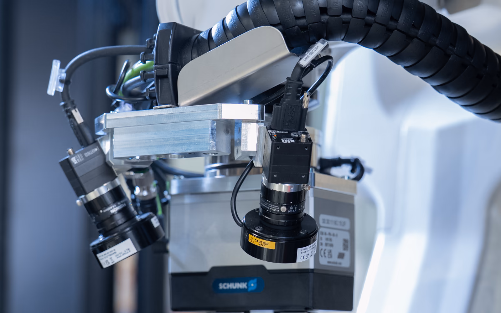 Two ring-lit MIRAI cameras mounted beside a two-finger gripper on the wrist of a robot arm